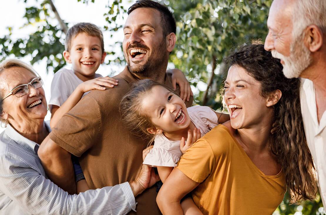 Cheerful multi-generation family having fun in nature. Parents are piggybacking their kids.