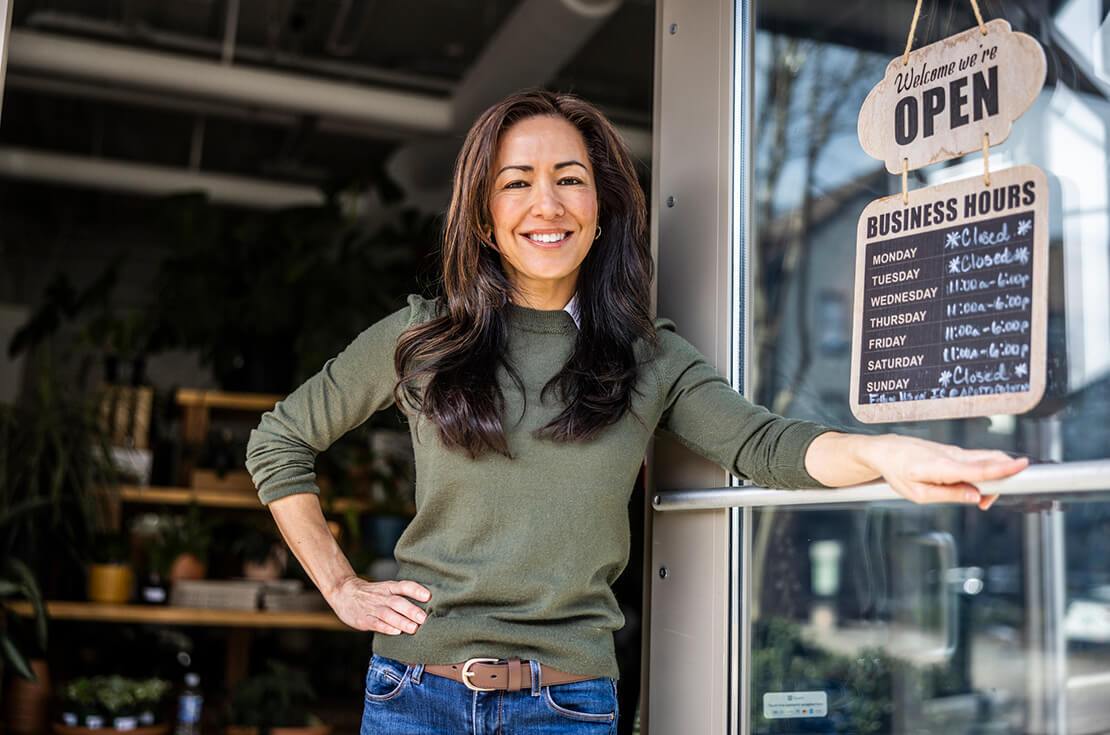 Portrait of proud female flower shop owner in front of open sign